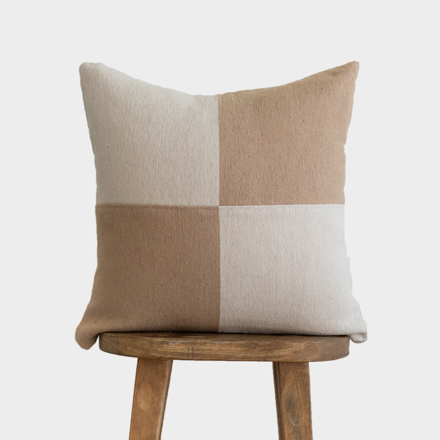 Tan and cream check patterned 22" pillow cover displayed on a wooden chair.