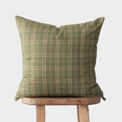 Green plaid pillow with red and cream stripes displayed on wooden chair.