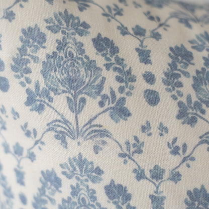 Blue floral and leaf pattern on cream linen fabric with textured weave.