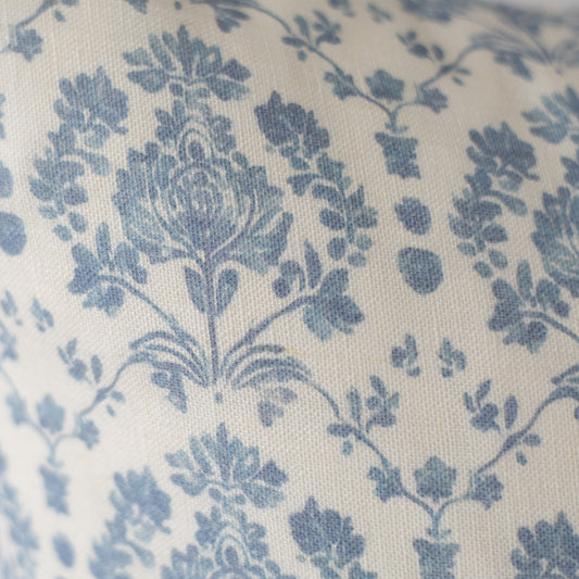 Blue floral and leaf pattern on cream linen fabric with textured weave.