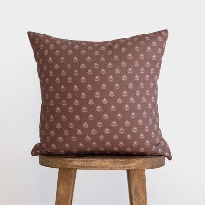 Brown cushion with repeating cream damask pattern, displayed on wooden chair.