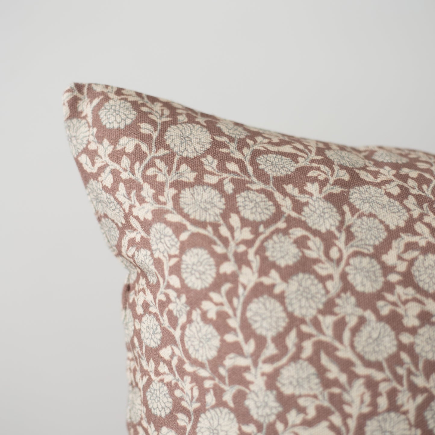 Throw pillow with cream and mauve floral damask pattern on woven fabric.