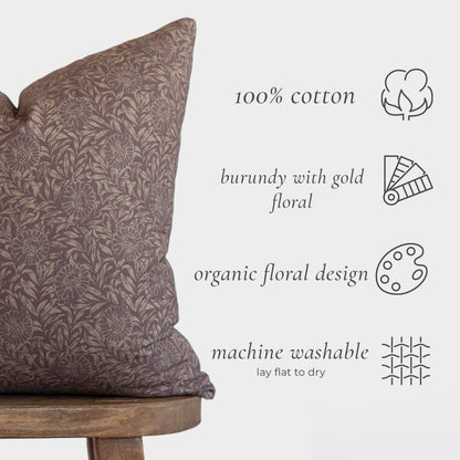 Burgundy cotton pillow with gold floral pattern displayed on wooden chair.