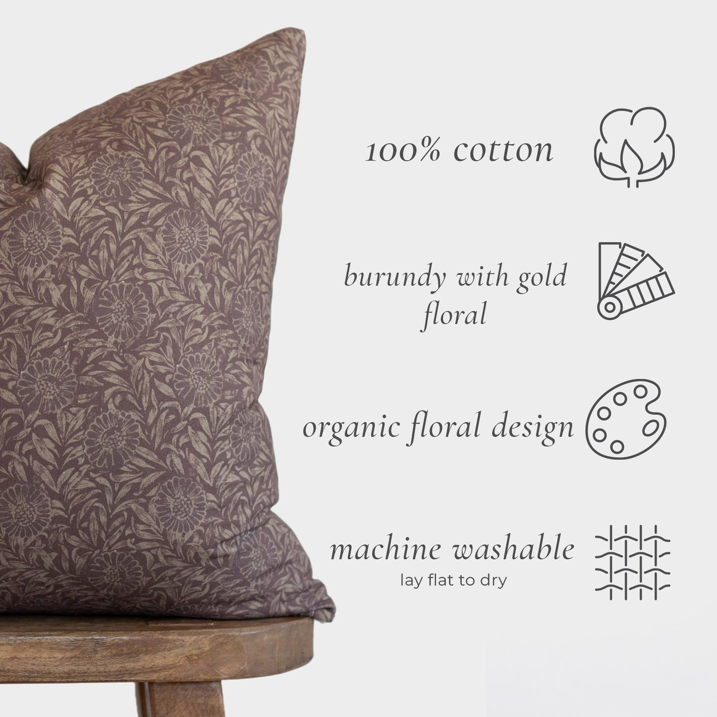 Burgundy lumbar pillow with gold floral pattern displayed on wooden chair.