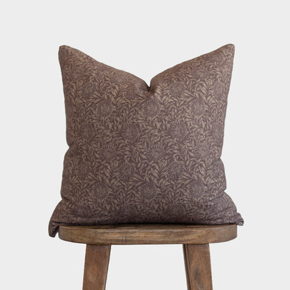 Brown damask patterned pillow with envelope back displayed on wooden stool.