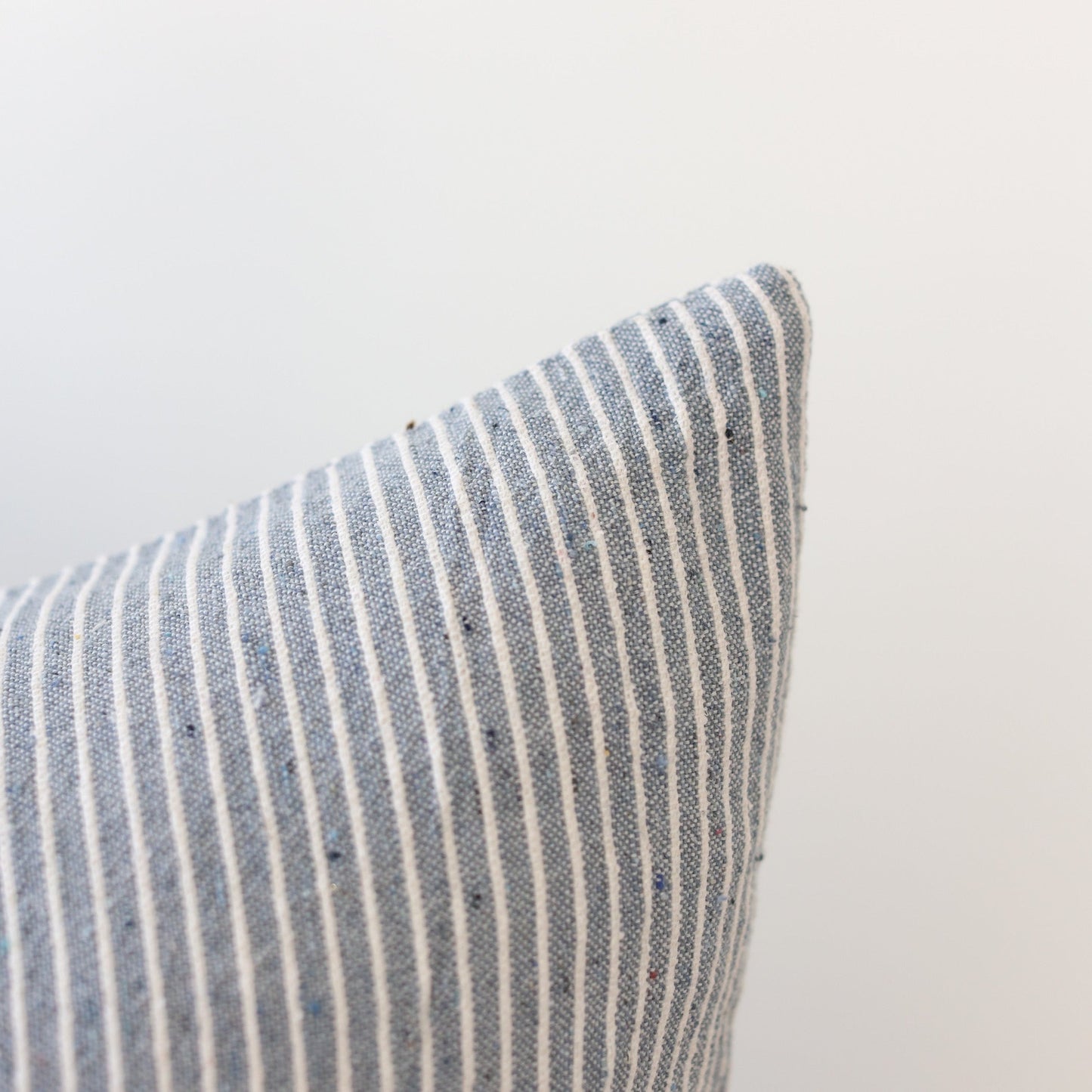 Blue and white striped pillow with textured woven fabric, shown at an angle against a neutral background.