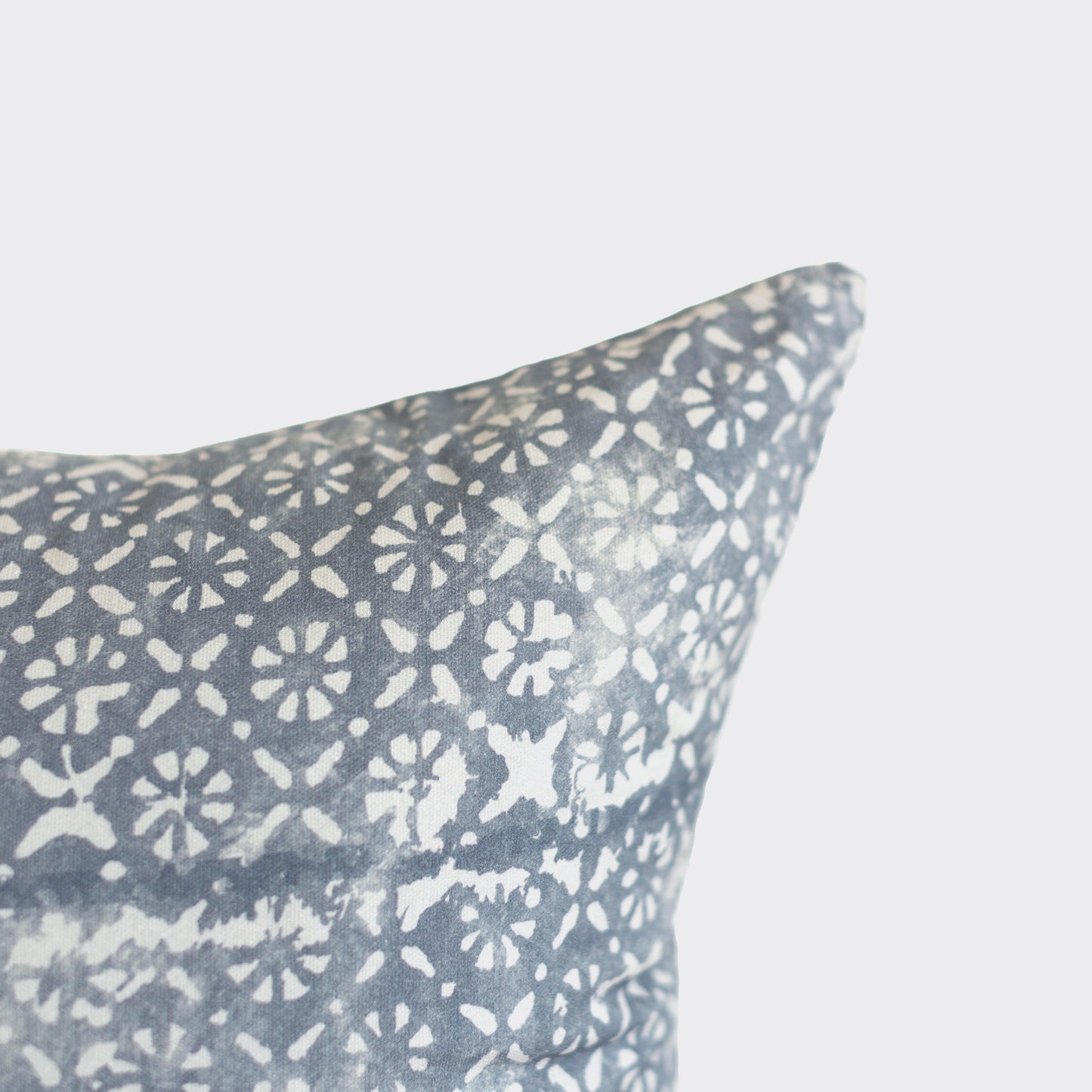 Blue-gray pillow with white diamond and floral geometric pattern.