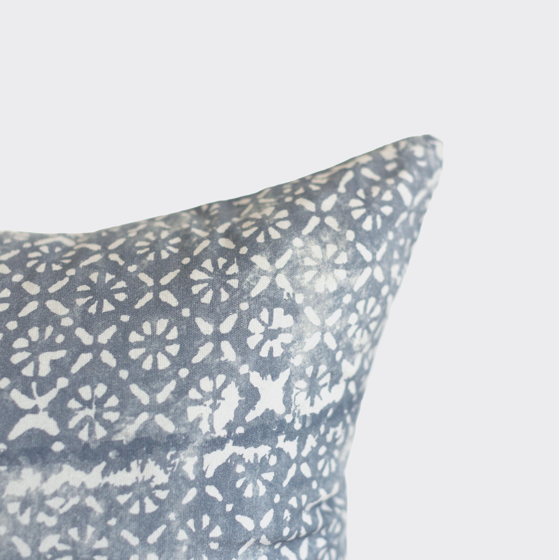 Blue-gray pillow with white diamond and floral geometric pattern.
