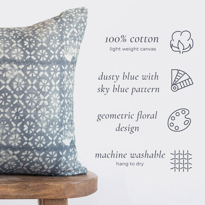 Dusty blue and cream geometric floral patterned pillow cover on wooden stool.