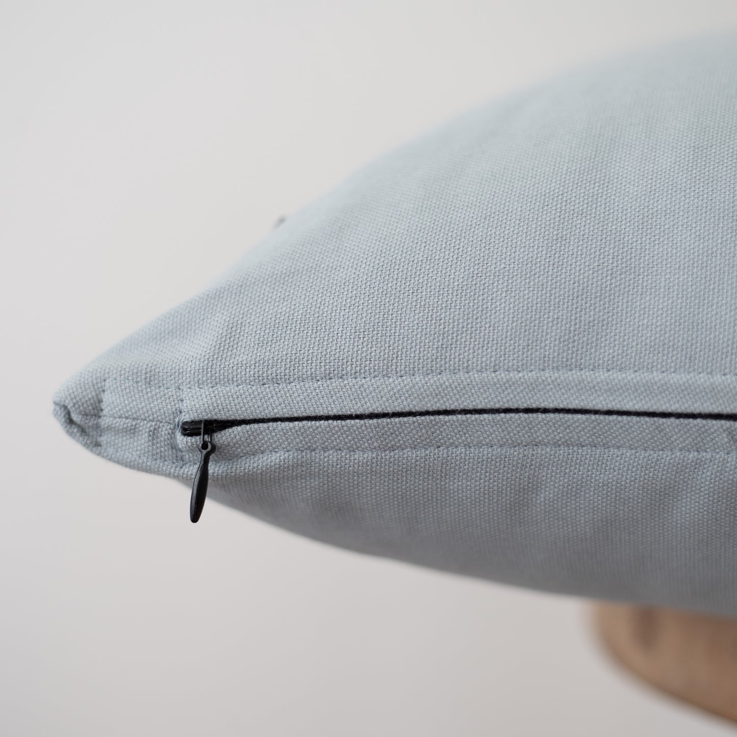 Dusty blue pillow cover with black zipper closure detail visible on seam.