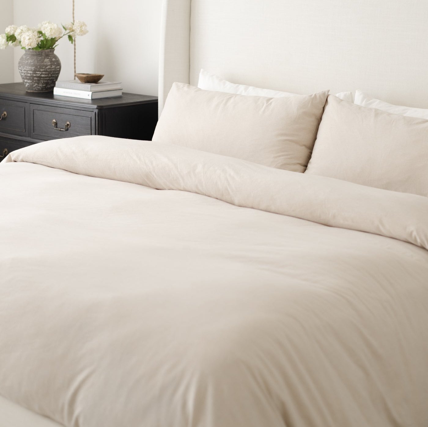 Beige duvet cover and pillowcases on a king bed with matching bedding and two decorative pillows.