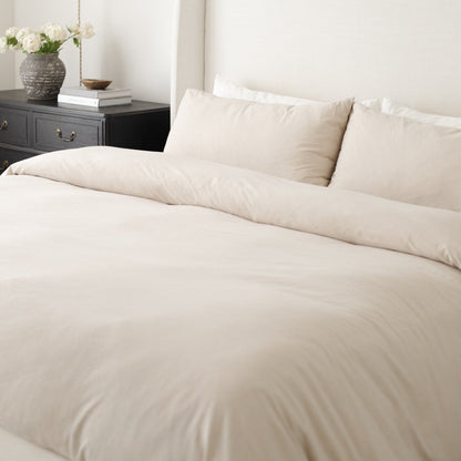 Beige duvet cover and pillowcases on a king bed with matching bedding and two decorative pillows.