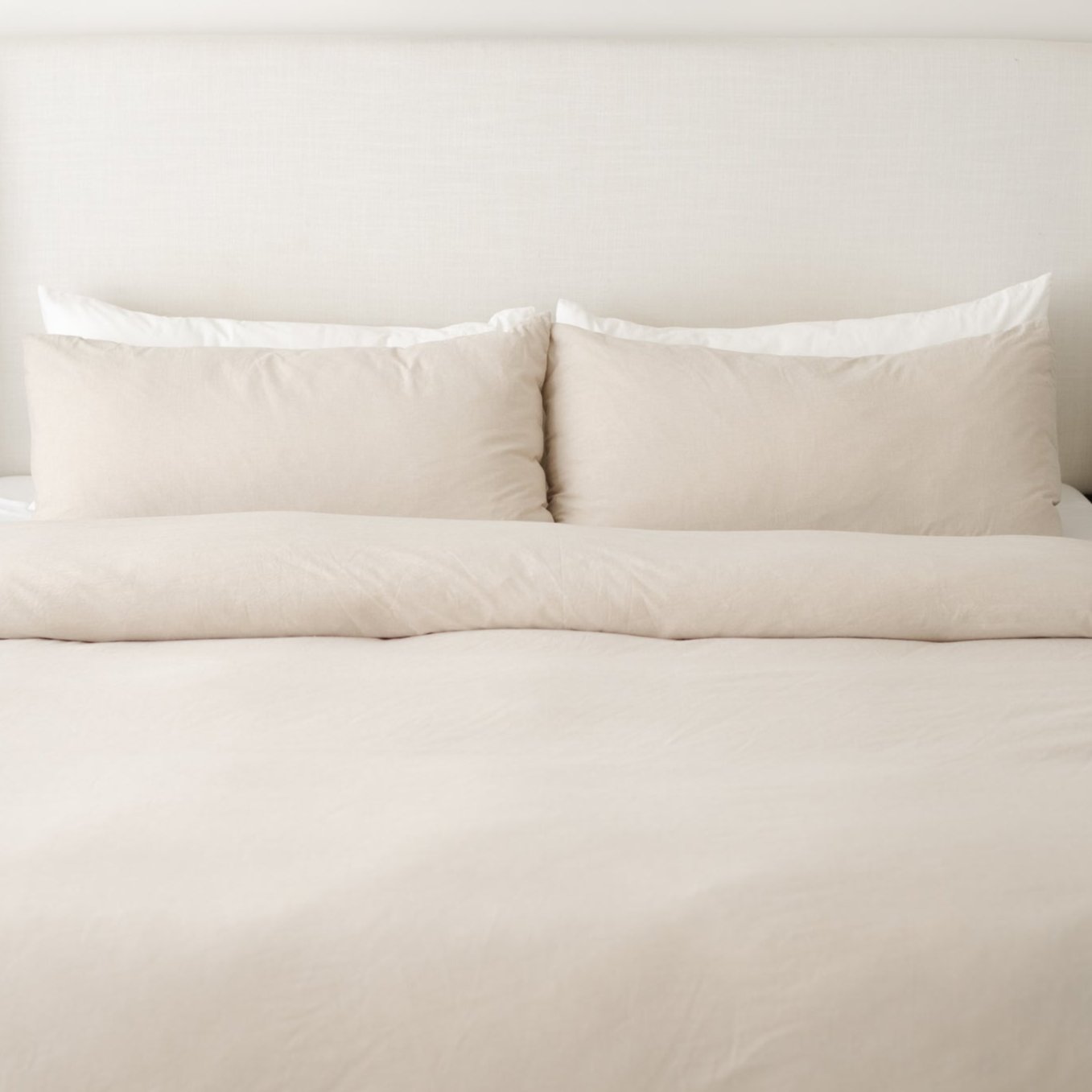 Beige duvet cover set with two matching pillowcases arranged on a bed.