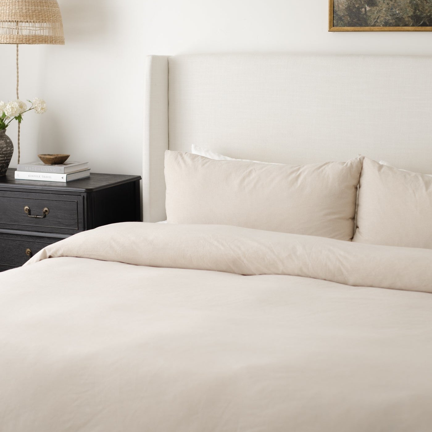 Beige duvet cover set on a king bed with matching pillowcases and upholstered headboard.