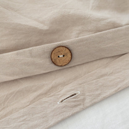 Beige duvet cover with wooden button closure and white pillowcase visible beneath.