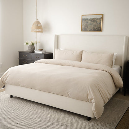 Beige duvet cover set on king bed with matching pillows and coordinating bedding.