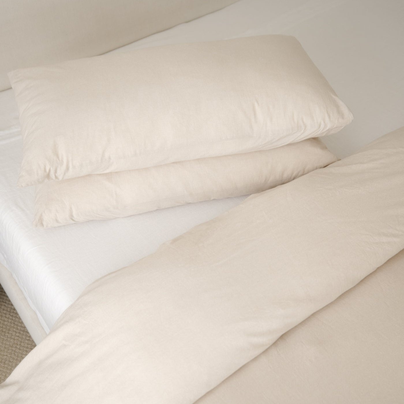 Beige duvet cover with two matching pillowcases arranged on a bed with white sheets.