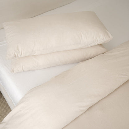Beige duvet cover with two matching pillowcases arranged on a bed with white sheets.