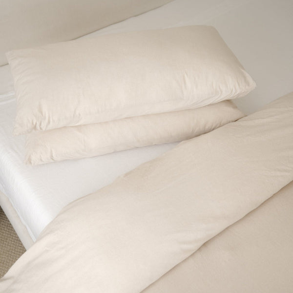 Beige duvet cover and white duvet insert with two pillows arranged on a bed.