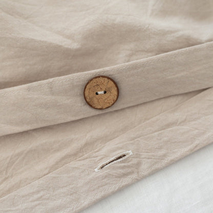 Beige duvet cover with wooden button closure and white duvet insert visible underneath.
