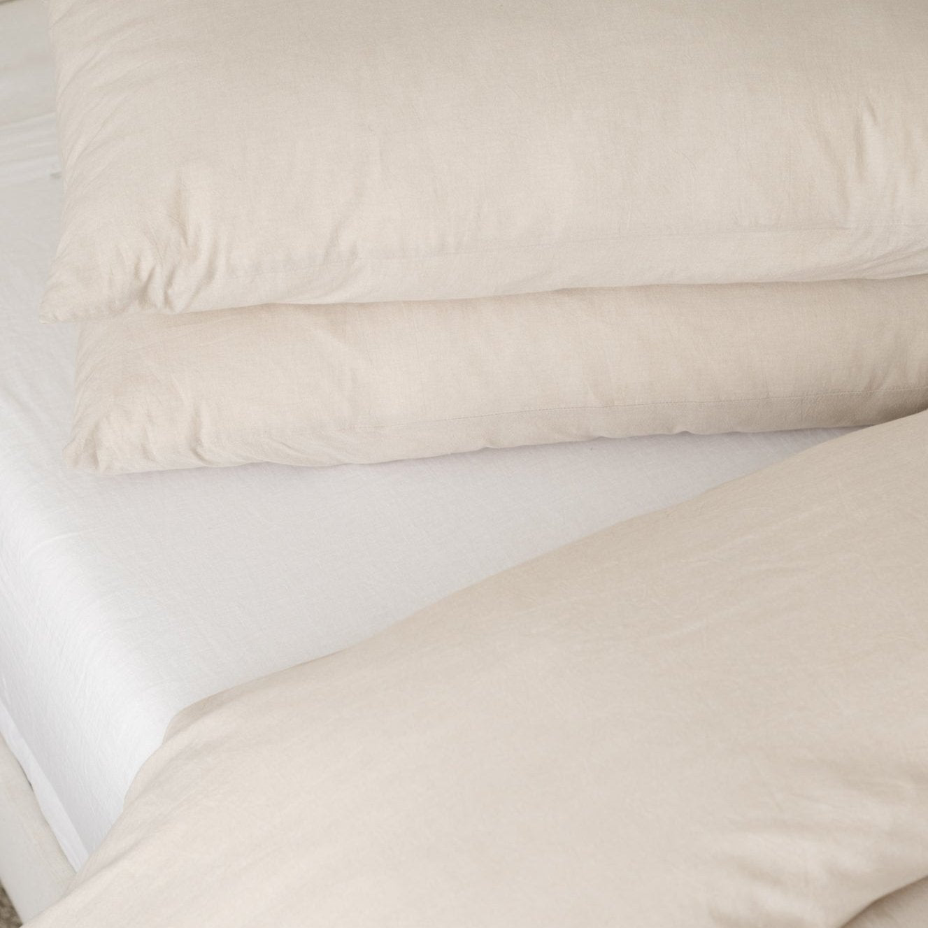 Beige duvet cover with two matching pillowcases arranged on a white mattress.