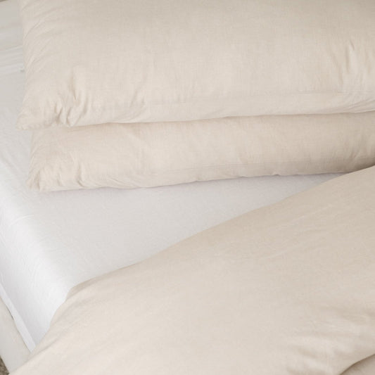 Beige duvet cover with two matching pillowcases arranged on a white mattress.