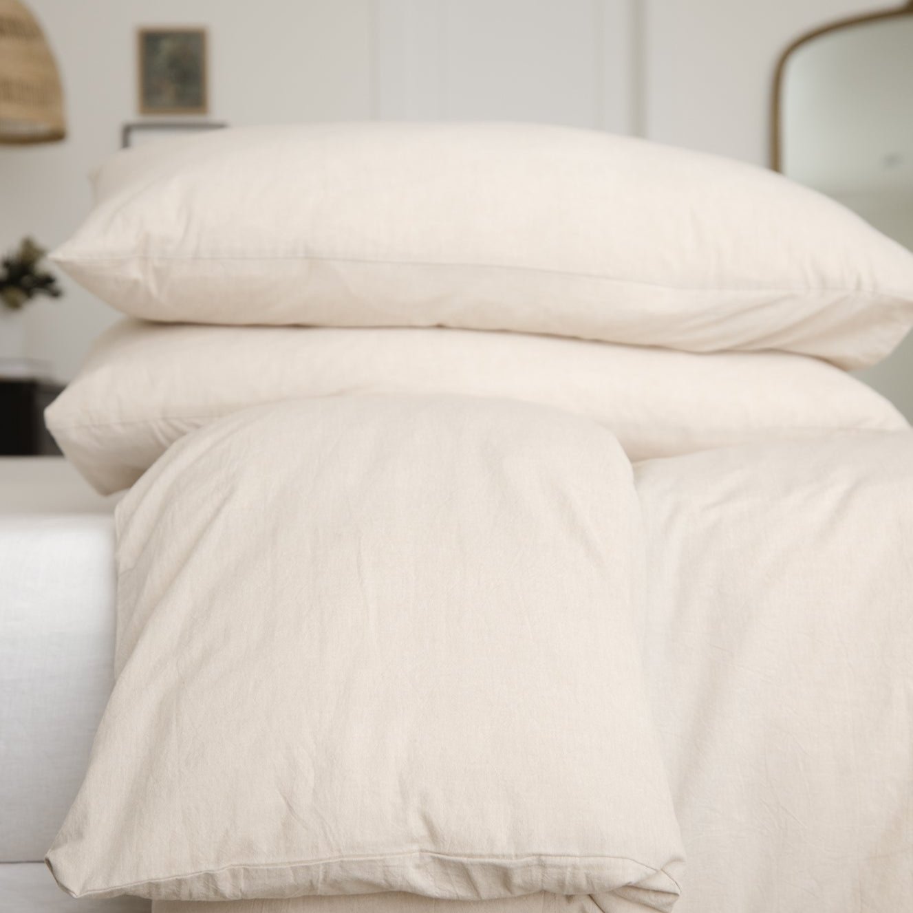 Beige duvet cover with two matching pillowcases arranged on a bed in a bedroom setting.