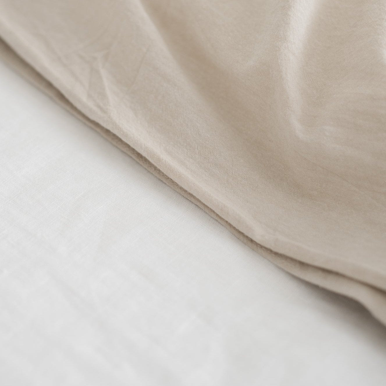Beige and white layered duvet cover showing soft woven fabric texture and fold detail.