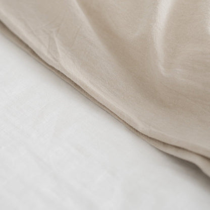 Beige duvet cover folded to show texture and layering with white insert beneath.