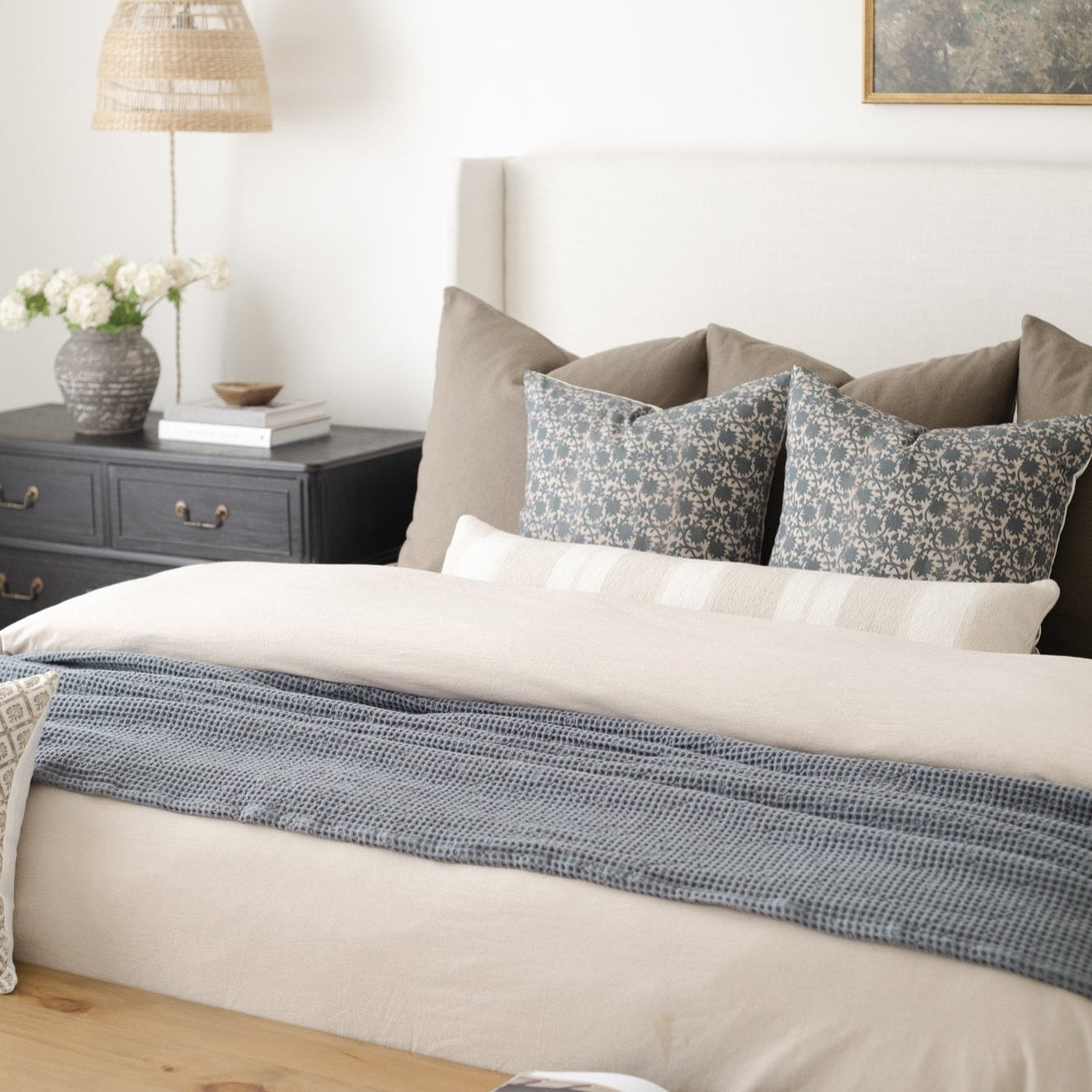 Beige duvet cover set on king bed with matching pillowcases and blue patterned throw blanket.