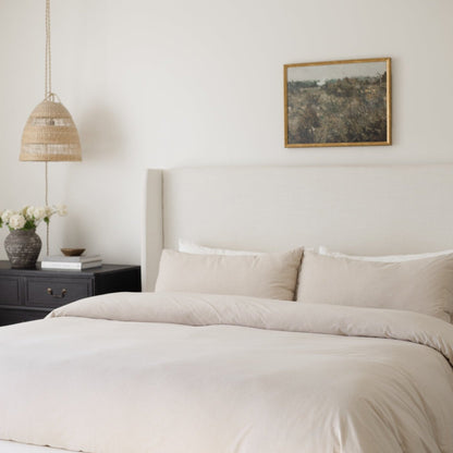 Beige duvet cover and pillowcases on a king-size bed with upholstered headboard.
