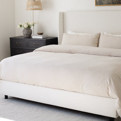 Beige duvet cover and pillowcases on a king bed with matching throw pillows.