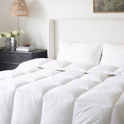 White quilted duvet insert with diagonal stitching pattern displayed on bed with pillows.