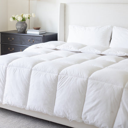 White quilted duvet insert on king bed with white pillows and upholstered headboard.