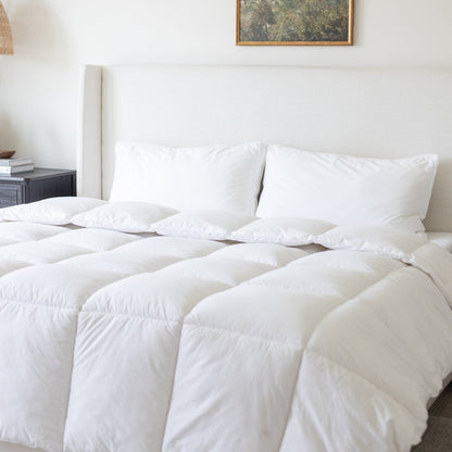 White quilted duvet insert with matching pillows on a bed with beige headboard.