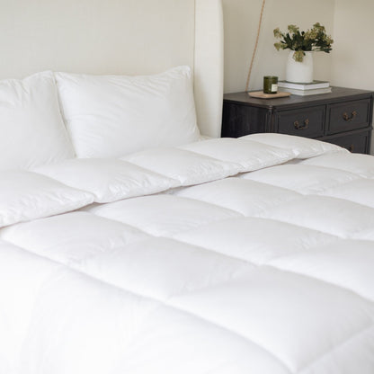 White quilted duvet insert on king-size bed with two matching pillows.
