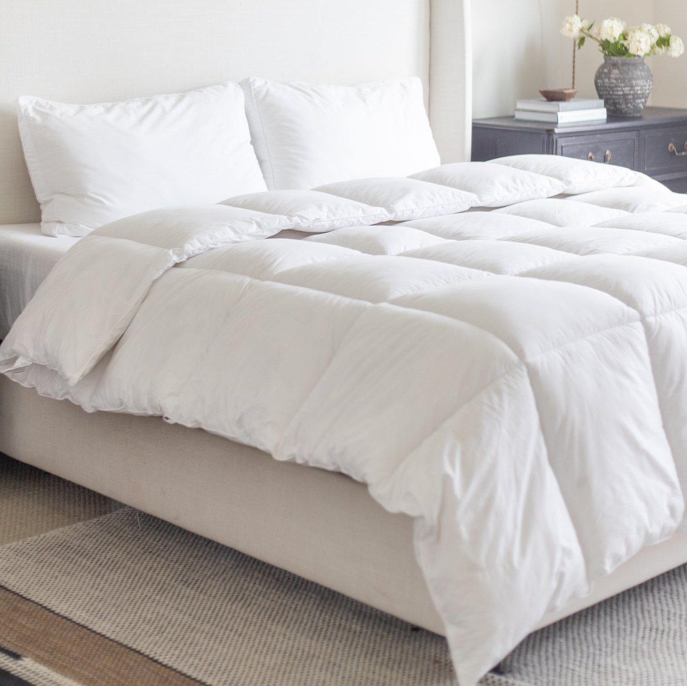White quilted king duvet insert on bed with two pillows and headboard.