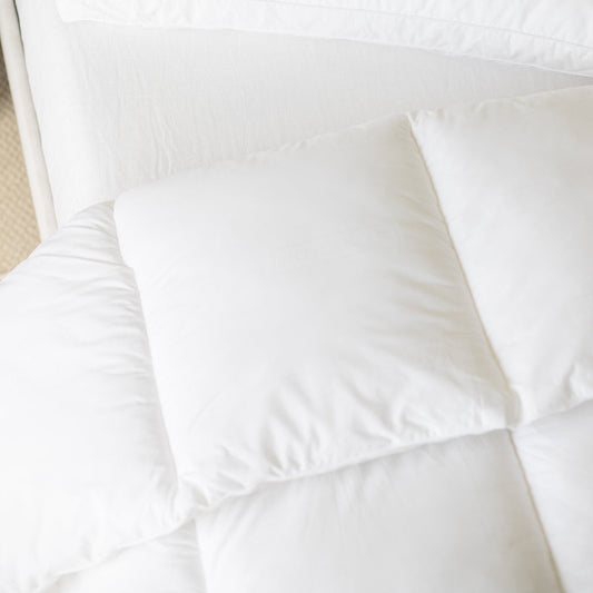 White quilted king duvet insert with internal baffle box construction, displayed flat on a bed.