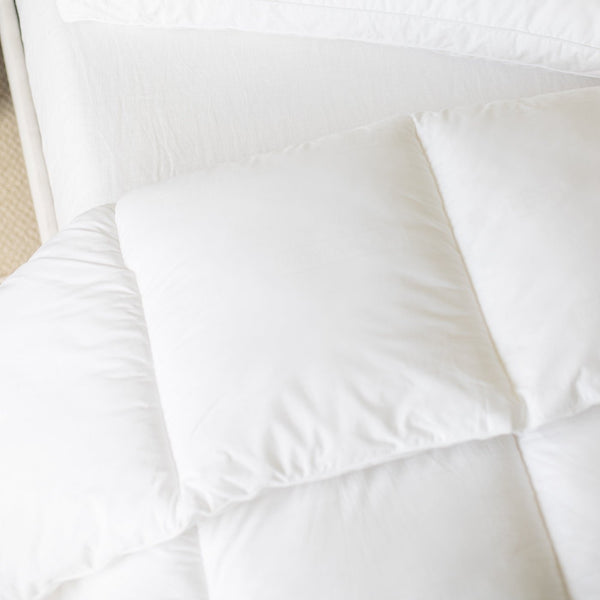 White quilted king duvet insert with internal baffle box construction, displayed flat on a bed.