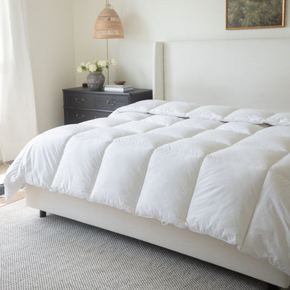 White quilted duvet insert on king-size bed with pillows and bedside dresser visible.