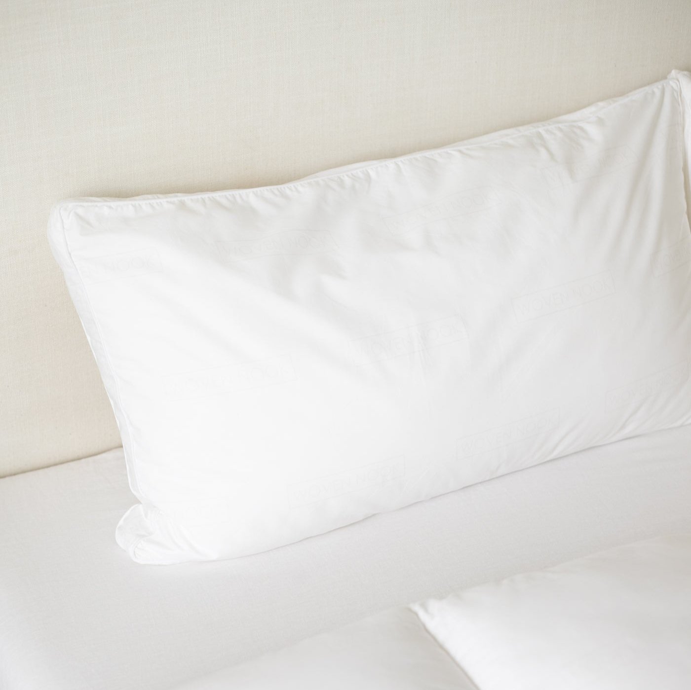 White faux down pillow insert in king sham size displayed on neutral bedding.