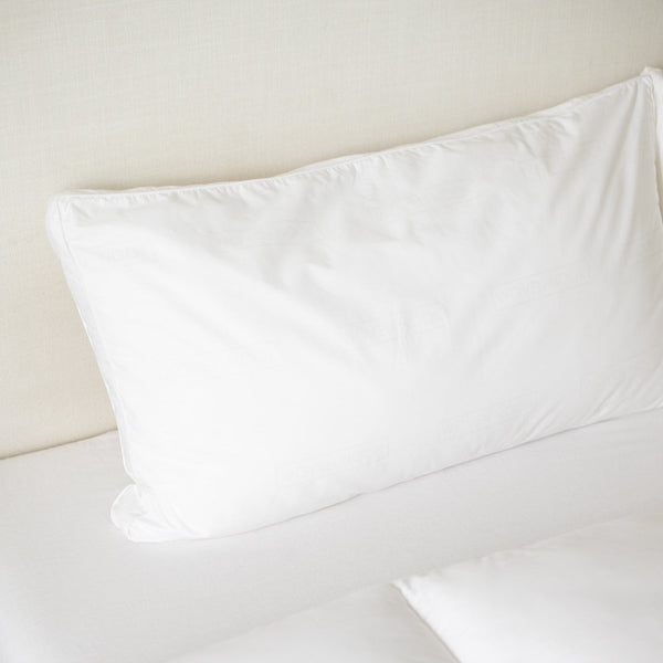 White faux down pillow insert in king sham size displayed on neutral bedding.
