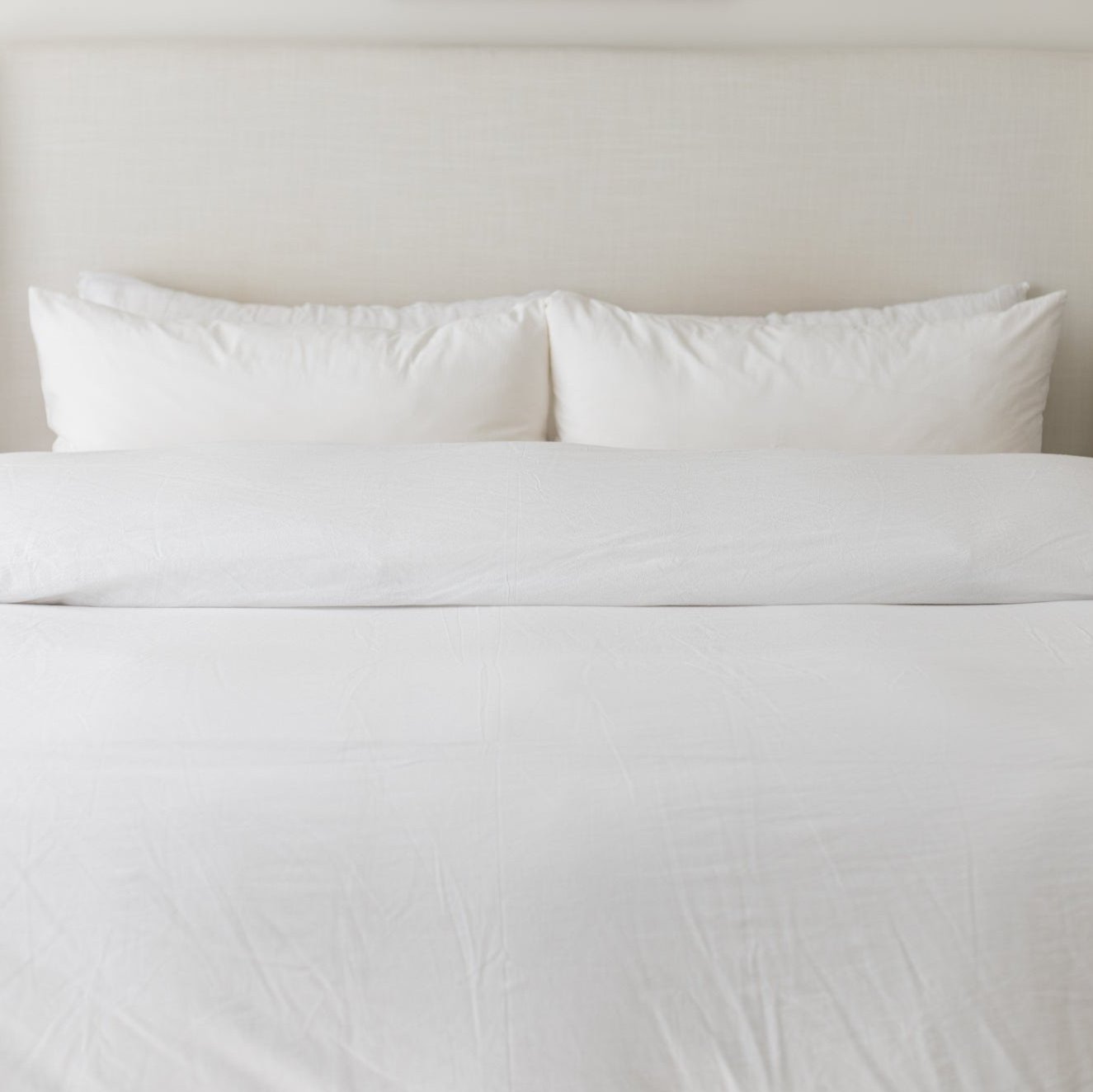 White duvet cover set on king-size bed with matching pillows and textured fabric.