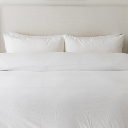 White duvet cover set on king-size bed with matching pillows and textured fabric.