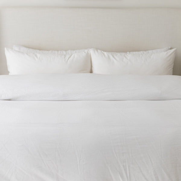 White king-size duvet cover set with two pillows and duvet insert on bed.