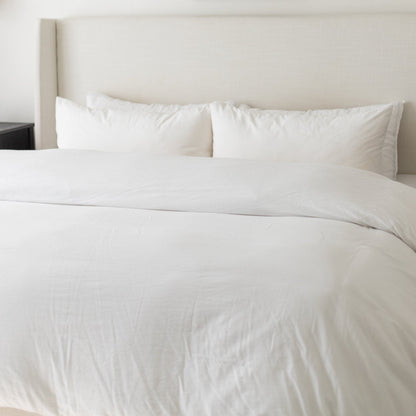 White duvet cover set on king-size bed with two matching pillowcases and neutral headboard.