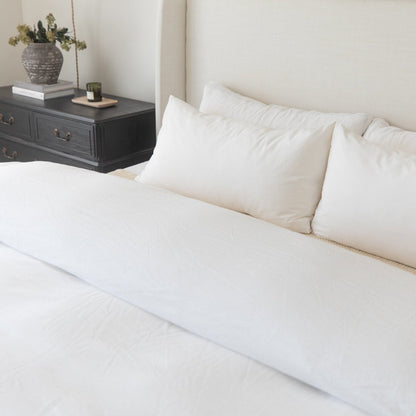 White duvet cover set on king bed with matching pillowcases and black nightstand.