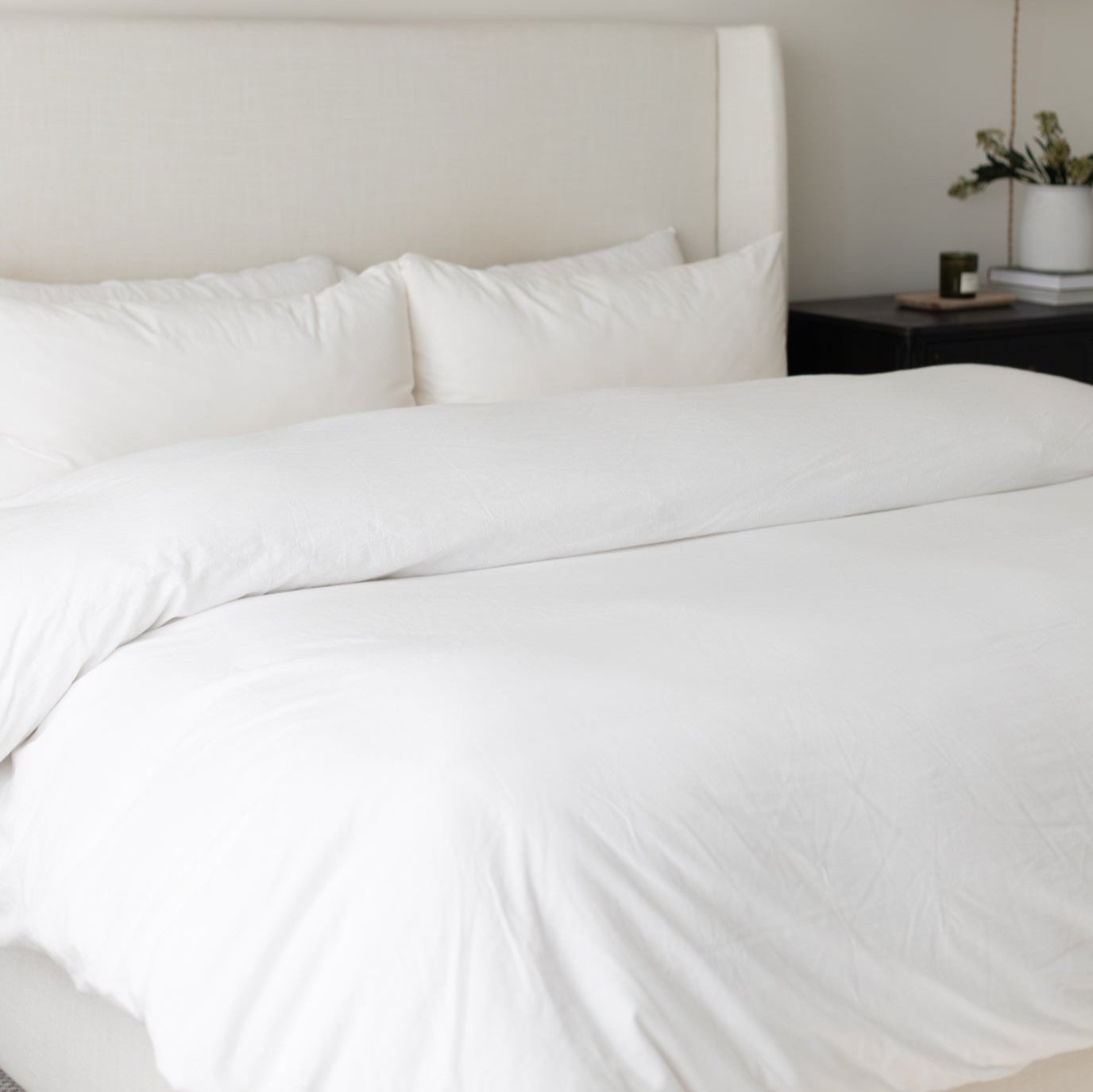 White duvet cover set on king-size bed with matching pillows and upholstered headboard.