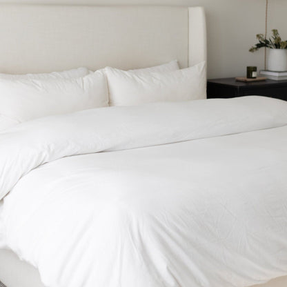 White duvet cover set on king-size bed with matching pillows and upholstered headboard.