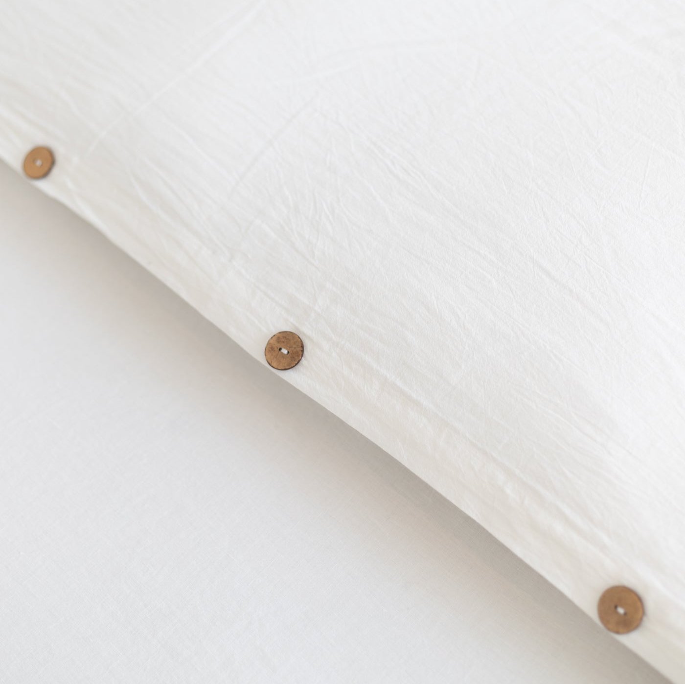 White duvet cover with wooden button closures, shown at an angle.